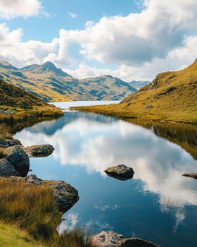 Mountain valley with a lake reflecting the blue sky and clouds on a sunny day