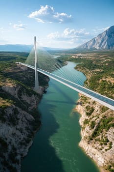 Aerial view of a modern cable-stayed bridge crossing a scenic river canyon, showcasing impressive engineering and natural beauty