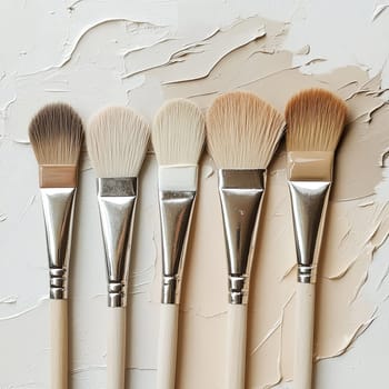 Five distinct art brushes with varying bristle styles are aligned neatly on a textured white background, highlighting their unique characteristics and potential uses.