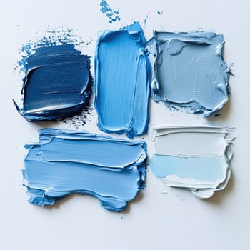 Different shades of blue paint are arranged on a white canvas, displaying various textures and tones that create a harmonious color palette.