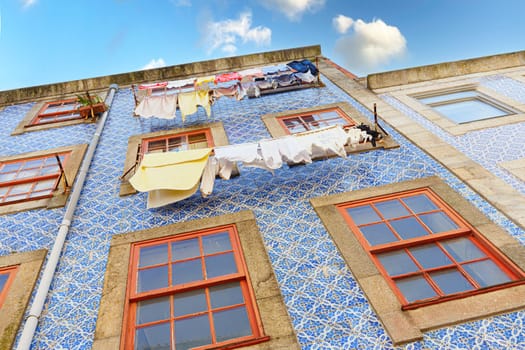 Facade of a house in Porto with typical tiles and clothes hanging on a summer day