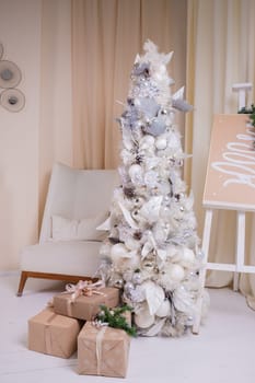 Decorated gold Christmas tree with golden patchwork ornament artificial star hearts presents for new year in white interior