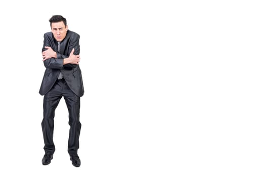 Full body of male in suit embracing himself and feeling cold on white background in studio while looking at camera