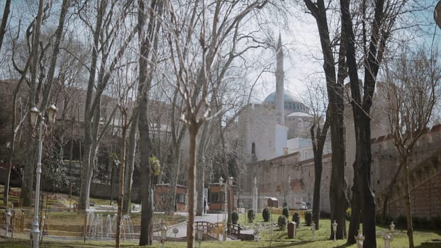 Green spring park with a church behind bald trees. Action. Natural background with a city park and a stone building behind