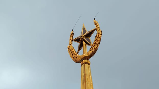 Soviet symbol, golden spire on a cloudy sky background. Stock footage. Golden star and ears of wheat