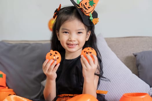 Cute little child girl with pumpkin balloon. Happy family preparing for Halloween.