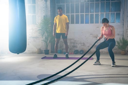 Fitness athletes training using battle ropes intense workout team exercise challenge in gym friends enjoying healthy bodybuilding endurance practice lifestyle together slow motion. High quality 4k footage