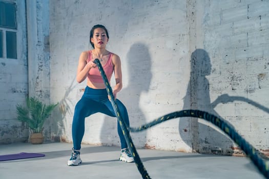 Fitness Chinese athlete training using battle ropes intense workout exercise in gym healthy lifestyle bodybuilding endurance practice in slow motion. High quality 4k footage
