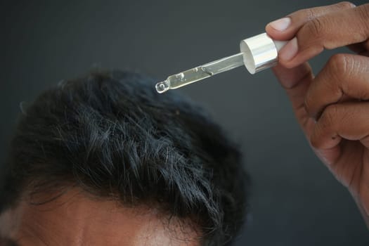 young men applying essential oils on his hair .