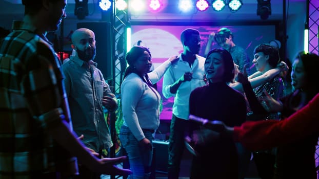 Young partners dancing together at club, enjoying slow music to dance in pairs. Romantic couples having fun with friends at social gathering clubbing event, attending modern party. Handheld shot.