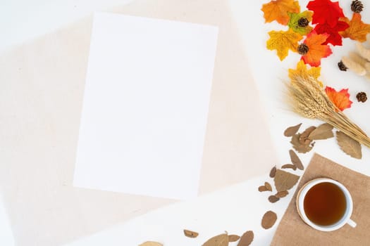Modern office desk with coffee cup, notebook, yellow-red autumn leaves on white background with copy space. Place for your text. Work table with office supplies. concept cosy, cozy, seasonal autumn.