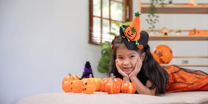 Cute little child girl with pumpkin balloon. Happy family preparing for Halloween.