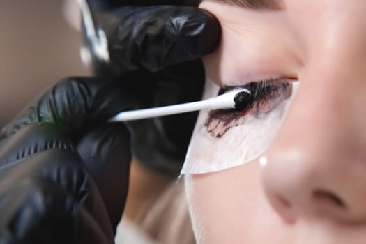 Eyelash procedure with master and client in a beauty salon. close-up of a model's eye, eyelash tinting process.