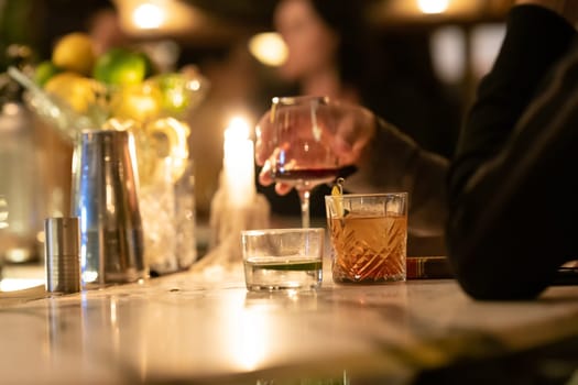 People drink alcoholic beverages at the bar. Mid shot