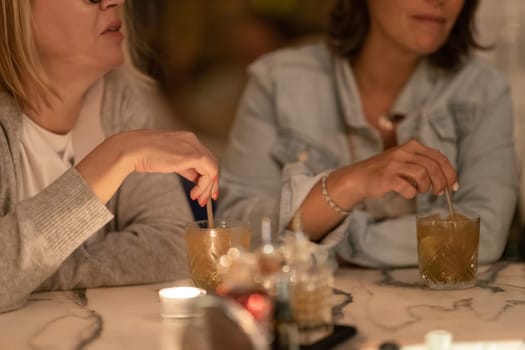Women drinking alcoholic cocktails at the bar at the table. Mid shot