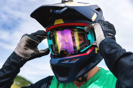 A professional well-equipped cyclist stands and adjusts his safety glasses, portrait. Freeride and off-road concept on a bicycle or motorcycle