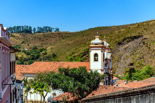 Tower of historic baroque church among the houses, roofs and hill in the city of Ouro Preto in Minas Gerais