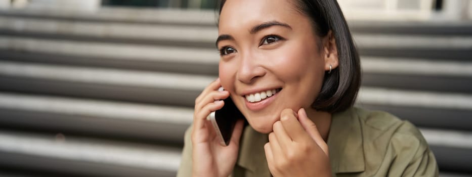 Close up portrait of asian girl talks on mobile phone. Young woman having a phone call, using her telephone.