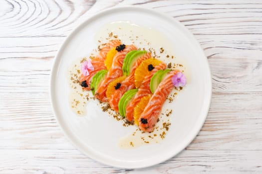 Salmon ceviche with avocado, orange and mango salsa on a light wooden background