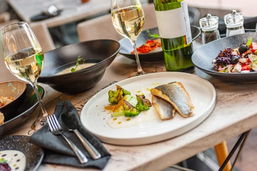 Dorado or sea bass fillet in cream sauce with broccoli on a white plate. High quality photo