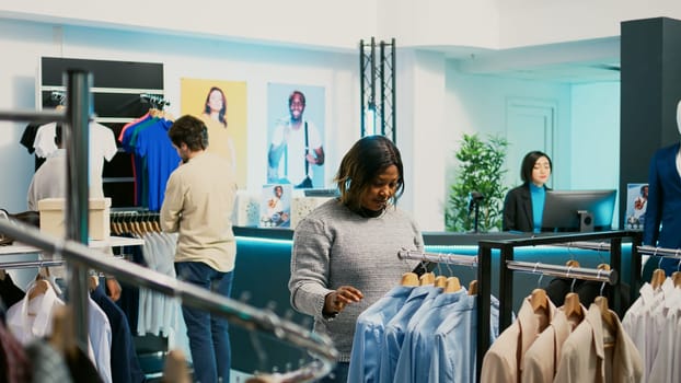 African american girl checking online market stock at mall, using smartphone to look at trendy new merchandise. Young woman shopper examining new fashion collection, small business concept.