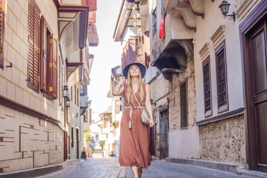 Happy woman tourist on background of old street of Antalya. female tourist traveler discover interesting places and popular attractions and walks in the old city Kalechi of Antalya, Turkey. Turkiye.