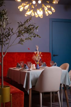 at a set table in a room with blue walls and a red sofa.