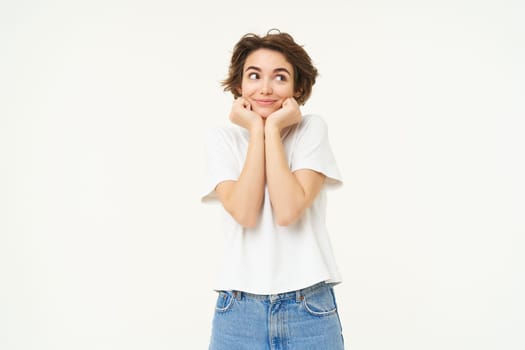 Portrait of cute brunette woman, looking with admiration and excitement, standing over white background.