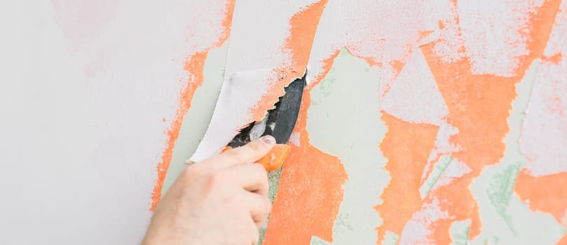 Young man using spatula and plastering of wall with white fresh finishing putty. Closeup. Repair work of home. Empty place for text. Side view