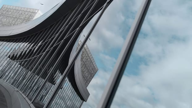 Cinematic reflection of glass building. Stock footage. Beautiful shooting angle with reflection in windows of building. Modern glass building with reflection of city and sky.