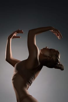 Graceful girl in ligerie with gold bodyart profile shot in the dark room