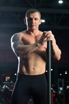 Tattooed shirtless male athlet full-length shot in sports gym