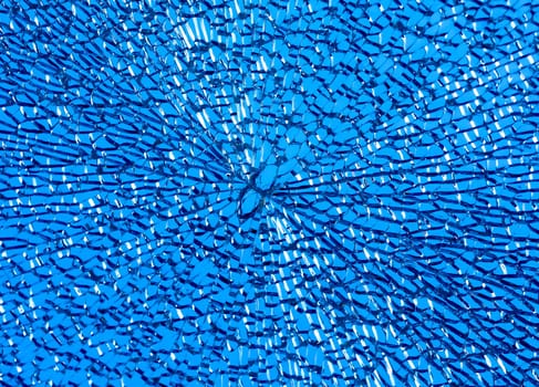Broken glass texture. The broken glass creates an abstract design with sharp shards fanning out in all directions. Cracked glass pattern resembling a spider web with light refracting off each fragment