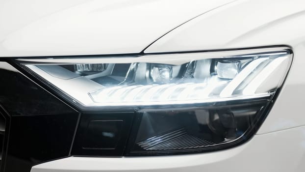 Bright luminous headlight. Action.A white foreign car with an iridescent large headlight. High quality 4k footage