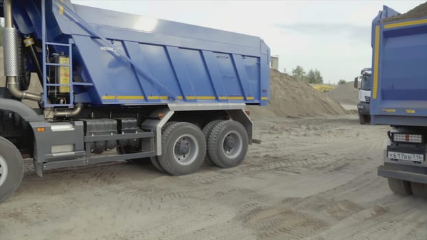 Serbia, Belgrade - July 30, 2021: Dump trucks replacing each other. Scene. Dump trucks are driving on construction site. Changing dump trucks on site with sand and earth.