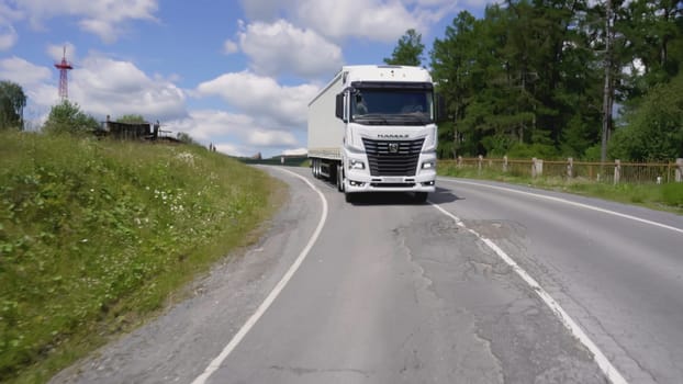 Serbia, Belgrade - July 30, 2021: Leading trucker on truck on highway. Scene. Big white truck is driving on highway in summer. Long-distance truck travels along country highway in summer.
