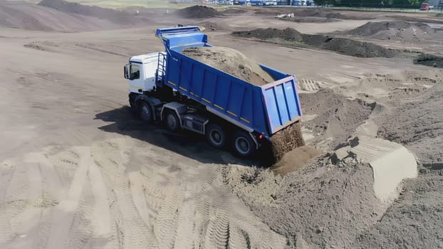 Top view of dump truck unloading sand. Scene. Dump truck dumps sand or earth on construction site. Land for construction site.