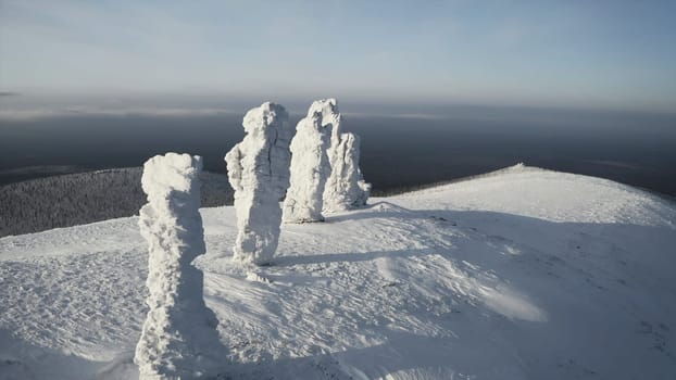 Stone pillars on hill in winter. Clip. Top view of stones standing on hill in winter. Snow-covered stone pillars on mountain on sunny winter day.