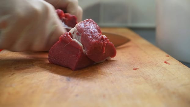 Close-up of slicing red piece of meat. Clip. Professional slicing of meat for steaks. Juicy beef meat is cut into pieces for dish.