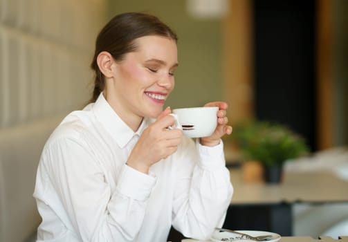 Side view of a beauty successful woman laughing while drinking coffee in a cafeteria