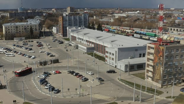 Town square of small town with trips. Action. Old gray city with square and building near railway. Top view of cars on square with railway station.