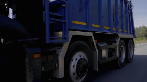 A huge blue truck. Scene.A truck with a blue body driving slowly along the highway is located next to a green forest. High quality FullHD footage