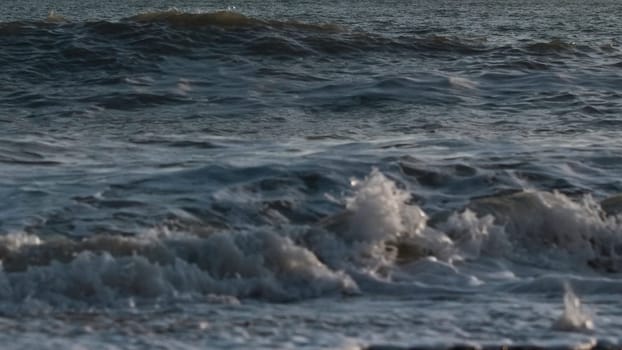 Close-up of slow waves on sea. Creative. Beautiful waves in slow motion on stone shore. Stone beach with beautiful waves at sunset.