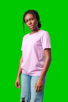 Young woman with curly hair shows a skeptical expression against a bright green background in studio