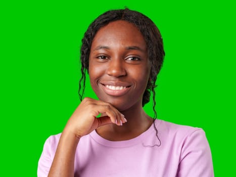 Young woman smiling joyfully in a pink shirt against a vibrant green background in a cheerful atmosphere close up