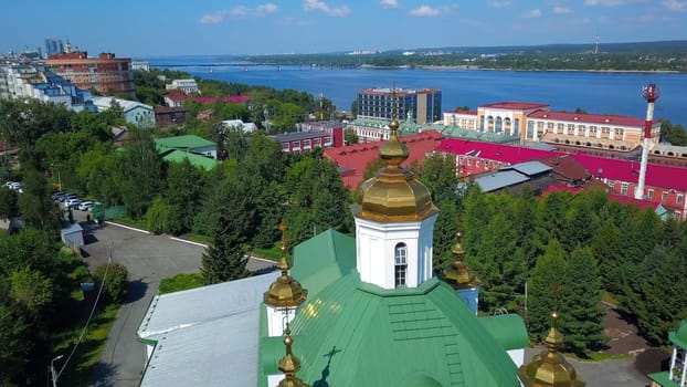 Aerial view of a summer city district with a church and houses. Clip. Beautiful green city located by the long river