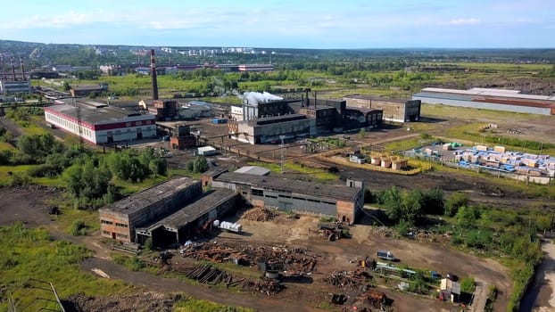 Urban industry from drone. Action. A view from a height to the outskirts with tall chimneys from where smoke comes out. High quality 4k footage