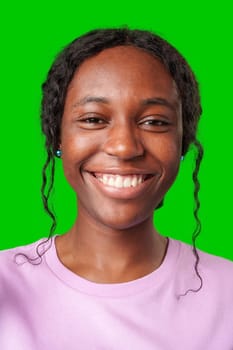 Young woman smiling joyfully in a pink shirt against a vibrant green background in a cheerful atmosphere close up