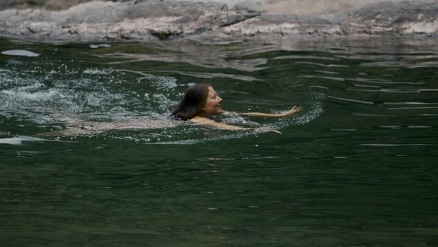 Woman swimming in the green lake or river. Creative. Concept of summer vacation, swimming in cold summer stream