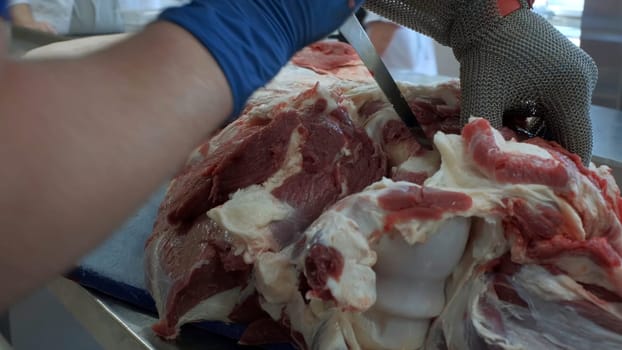 Production at a food factory.Clip. Raw meat is separated from bones by specially trained people in suits. High quality 4k footage